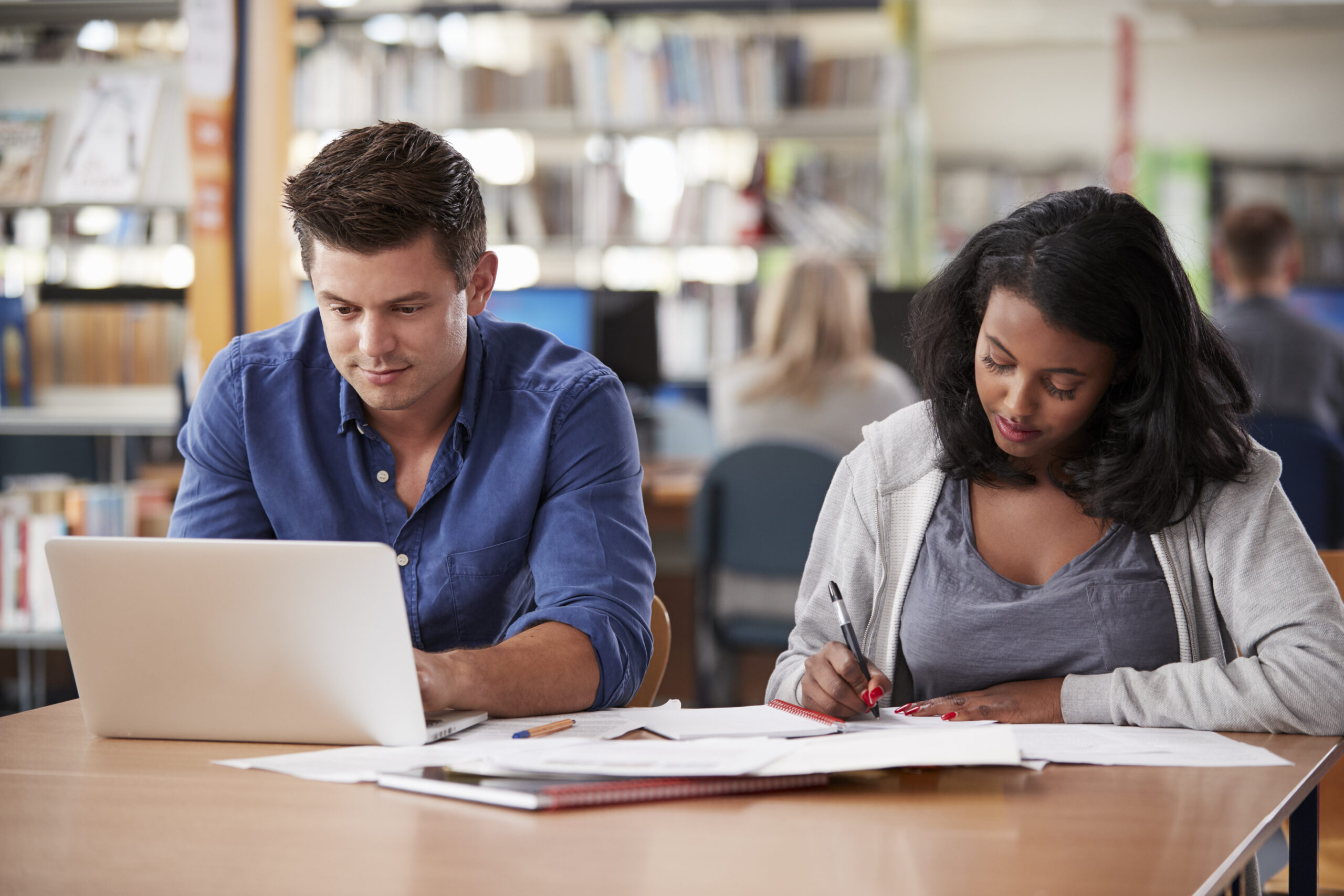 Two Mature Students Working On Laptop In College Library
